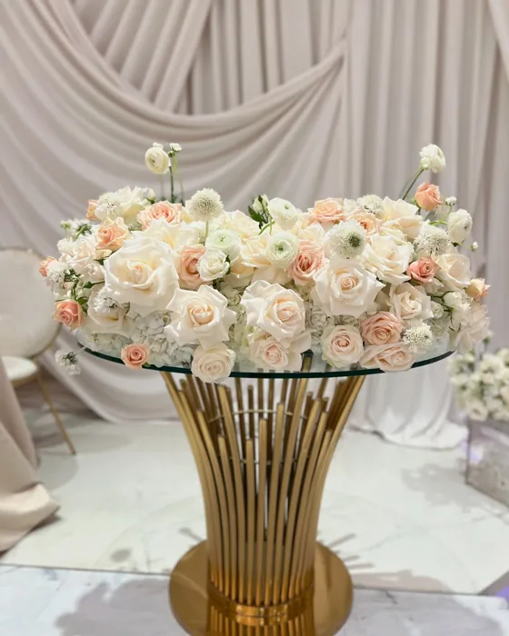 Blush rose and ranunculus centerpiece on a gold and glass table