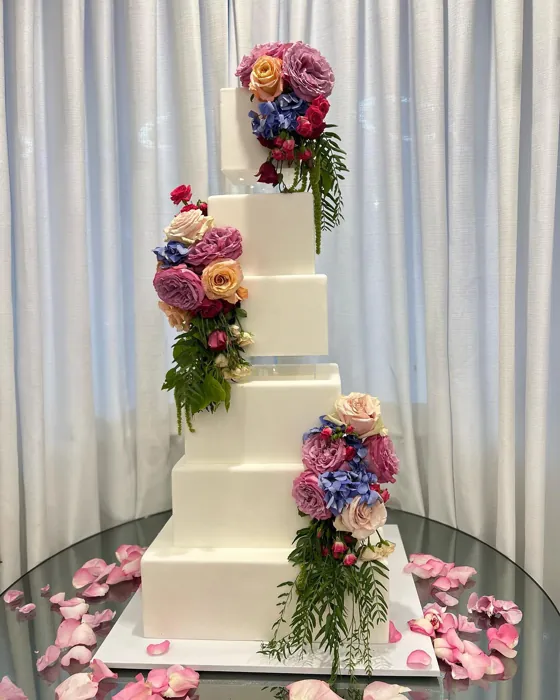 Tiered wedding cake decorated with a cascade of fresh flowers